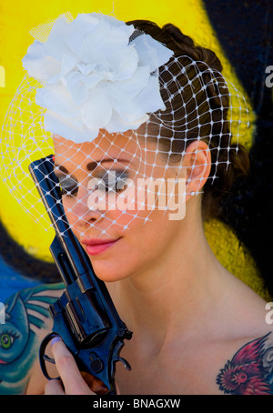 Tätowierte Braut vor Graffiti Hintergrund mit Handfeuerwaffe Stockfoto