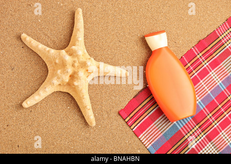 Sea Star und Sonnencreme auf einem sandigen Strand Stockfoto