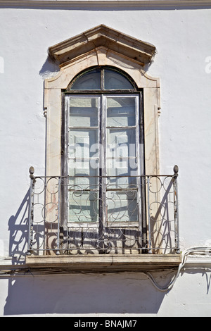 Braune rustikale Fenster mit schmiedeeisernen Balkon auf eine weiß verputzte Wand Stockfoto