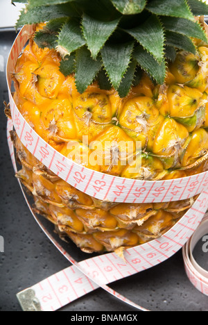 Reife lebendige Ananas auf einer schwarzen Platte mit Klebeband meter Stockfoto