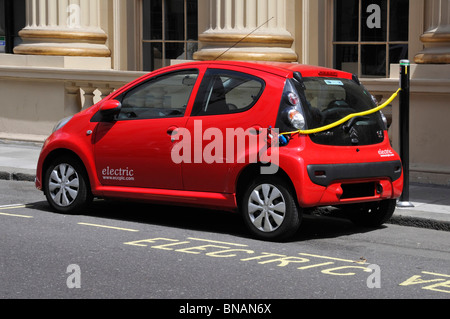 Elektro-Auto aufladen über öffentliche Ladestation auf Asphalt angebrachten Poller neben abgesteckten ausgewiesenen Parkplatz Bucht Westminster London England UK Stockfoto