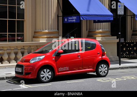 Klimawandel und Elektroauto, das in einer dafür vorgesehenen Bucht für Elektrofahrzeuge geparkt ist, die vom westminster City council an eine öffentliche Ladestation auf dem Bürgersteig angeschlossen ist Stockfoto