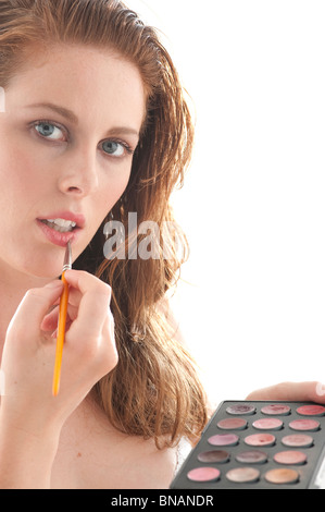 rothaarige Frau malt ihre Lippen Stockfoto