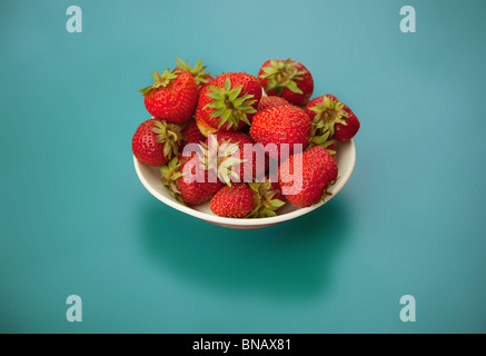 Erdbeeren in Schüssel auf blauem Hintergrund Stockfoto
