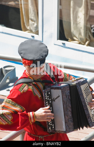 Mann in traditionellen russischen passen Palying an der Mundharmonika Stockfoto