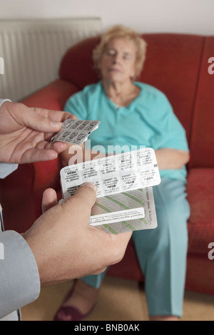 Männliche Hand mit Drogen, während ältere Patientin auf dem Sofa schläft Stockfoto