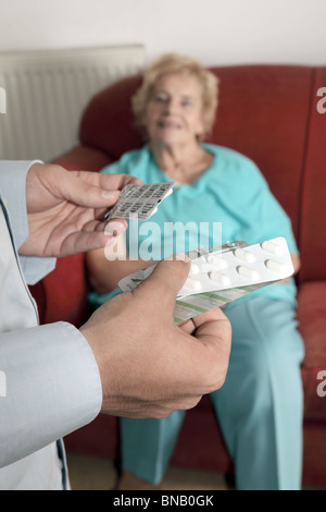 Männliche Hand mit Drogen, während ältere Patientin sitzt auf weiblich Stockfoto