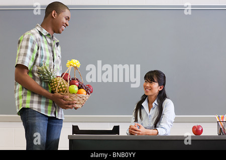 Männlichen High-School-Schüler geben Lehrer einen Korb mit Früchten Stockfoto