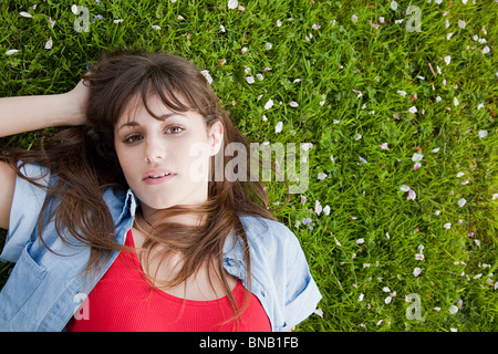 Junge Frau liegt auf dem Rasen Stockfoto