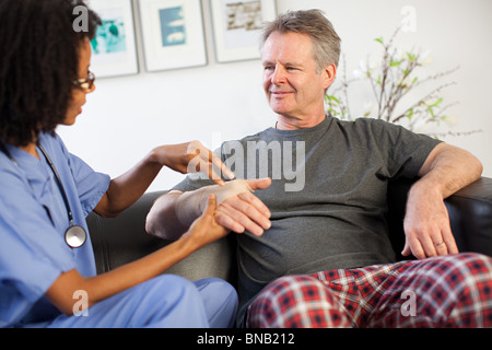 Krankenschwester besucht Mann mit Verletzung am Handgelenk Stockfoto