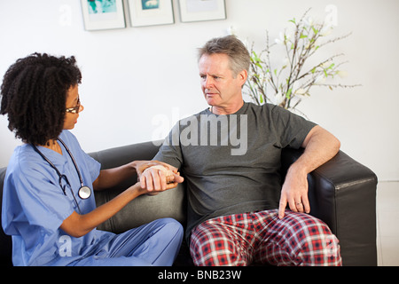 Krankenschwester besucht Mann mit Verletzung am Handgelenk Stockfoto