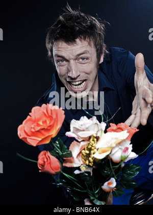 Studio-Porträt auf schwarzem Hintergrund einen lustigen expressive kaukasischen Mann mit Blumen Wut Stockfoto