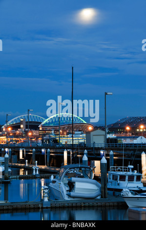 Twilight und Mondschein an einem Sommerabend mit Blick auf den Seattle-Stadion-Dächern und einen Teil der Bell Harbor Marina. Stockfoto