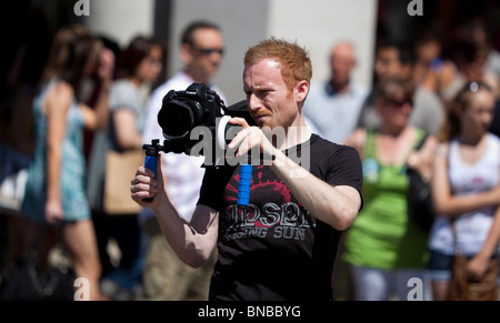 Videofilmer fotografieren mit einer digitalen DLSR-Kamera montiert auf einer Schulter Unterstützung Rig, London, England, UK Stockfoto