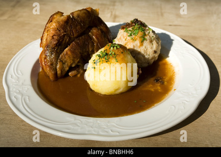 Das traditionelle bayerische Gericht Schweinshaxe (gebratenes Eisbein) serviert mit Kartoffel und Semmelknödel in München. Stockfoto