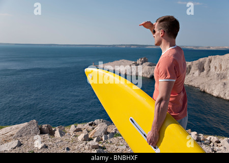 Mann mit Surfbrett Blick auf See Stockfoto