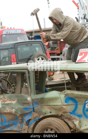 Banger Mechaniker Rennfahrer schlagen Schrott altes Auto mit Vorschlaghammer Stockfoto