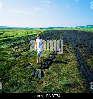 KLEINES MÄDCHEN FLANIEREN UNTER TROCKNUNG TORF ZIEGEL COUNTY KERRY IRLAND Stockfoto