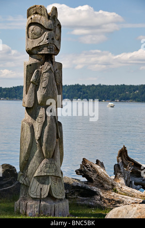 Ein Totempfahl steht auf der Küste von Blake-Insel mit schönen Puget Sound im Hintergrund. Stockfoto