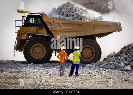 Minenarbeiter beobachten, wie ein großer LKW mit Erz in den wichtigsten Grube Youga-Goldmine in der Nähe der Stadt Youga, Burkina geladen wird Stockfoto