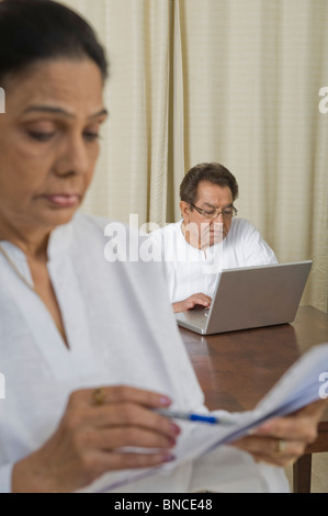 Aussortierung von Rechnungen mit einem Mann an einem Notebook im Hintergrund arbeitet Frau Stockfoto