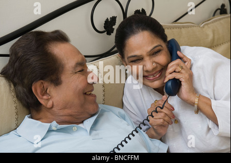 Frau im Gespräch am Telefon mit einem Mann auf dem Bett Stockfoto