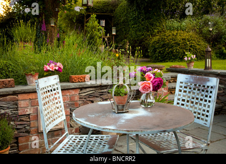 Metall-Tisch und Stühle auf der Terrasse mit Kerzen und Laternen im Garten in der Nacht Stockfoto