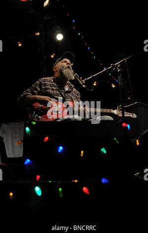 Bluesman Seasick Steve auf der Bühne mit seiner roten Boogie-Gitarre, umgeben von bunten Lichtern Stockfoto