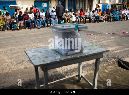 Menschen sitzen auf einer Bank in der Straße, während sie darauf warten, in einem Wahllokal in der Hauptstadt Accra bei Präsidentschaftswahlen zu stimmen Stockfoto