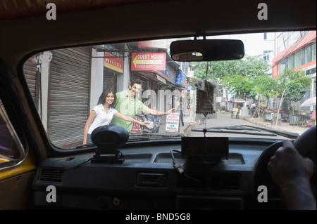 Paar stehen am Straßenrand Trampen, Kolkata, Westbengalen, Indien Stockfoto