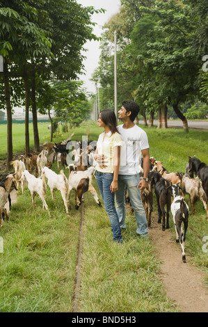 Paar stehend mit einer Herde von Ziegen in einem Feld, Kolkata, Westbengalen, Indien Stockfoto