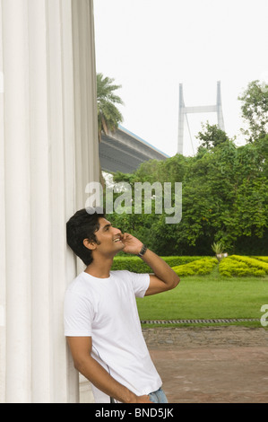 Mann telefonieren mit Handy bei James Prinsep Memorial, Vidyasagar Setu, Kolkata, Westbengalen, Indien. Brücke im Hintergrund Stockfoto