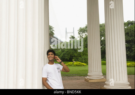 Mann telefonieren mit Handy bei James Prinsep Memorial, Vidyasagar Setu, Kolkata, Westbengalen, Indien. Brücke im Hintergrund Stockfoto