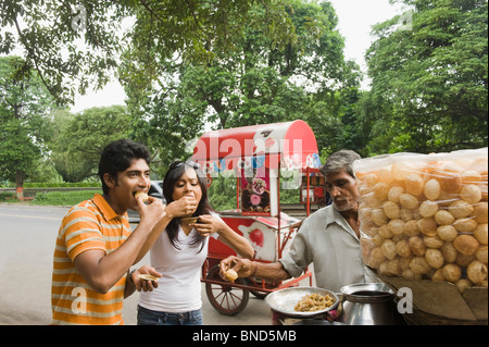 Anbieter mit indischen Snack Panipuri, ein paar auf einer Straße, Kolkata, Westbengalen, Indien Stockfoto
