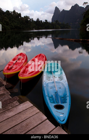 Drei Kajaks sind auf einem Holzsteg auf Cheow Lan Lake, im Khao Sok Nationalpark, Thailand gebunden. Stockfoto