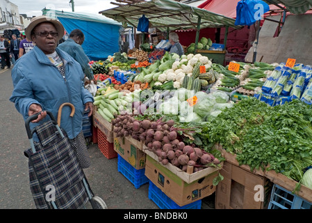 Eine ältere Frau Shopper mit steh-shopping Trolley von pflanzlichen Stall in Ridley Straße Markt Dalston London KATHY DEWITT Stockfoto