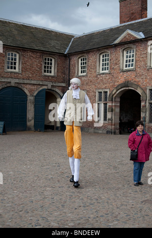 Mann auf Stelzen in mittelalterlicher Tracht außerhalb von historischen Gebäuden. Stockfoto