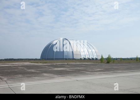 Weitläufiger Blick auf den ehemaligen Zeppelin-Luftschiff-Hangar, heute eine massive Kuppelstruktur unter blauem Himmel, an einem verlassenen Flugplatz in Deutschland. Stockfoto