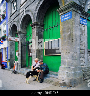 Zwei ältere Männer mit einem Border Collie Hund sitzt am Platz, Westport, County Mayo, Irland Stockfoto