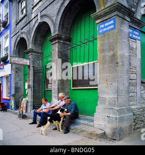 Drei Männer mit einem Border Collie Hund sitzt am Platz, Westport, County Mayo, Irland Stockfoto