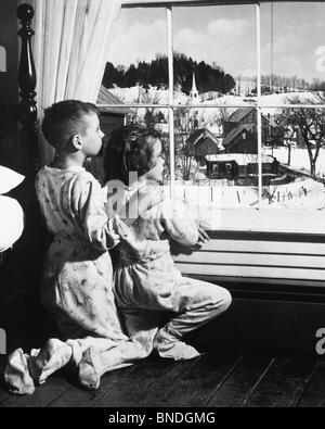 Rückansicht des einen Bruder und seine Schwester Blick durch ein Fenster Stockfoto