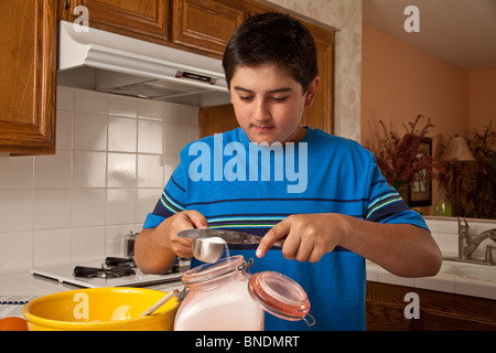 Hispanic Teenager trug ein blaues Hemd messen Zutaten kochen. Herr © Myrleen Pearson Stockfoto