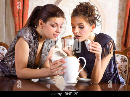 Zwei Freundinnen haben schon Tee getrunken und schauen Sie in eine leere Teekanne Stockfoto