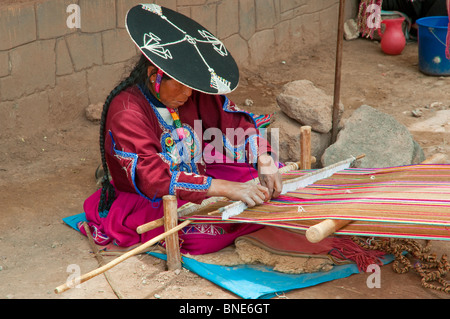 Eine peruanische Frau in traditioneller Kleidung Weben eine Decke auf dem Platz in Racchi, Peru, Südamerika. Stockfoto