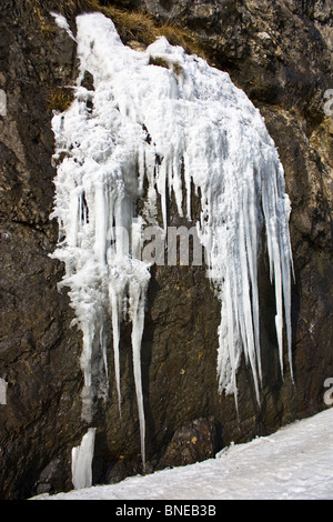 Kleinen gefrorenen Wasserfall auf braunen Felsen im winter Stockfoto