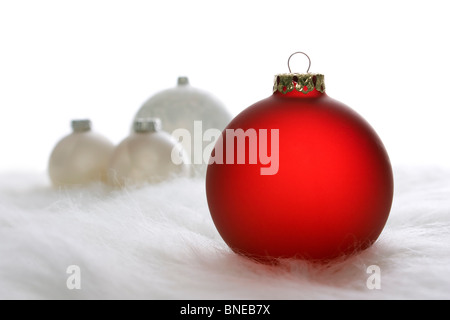 Anordnung der roten und weißen Weihnachtskugeln auf weißem Fell Stockfoto