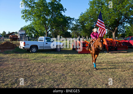 Cowgirl wehende Flagge im Viehhof vor Eröffnung des PRCA Rodeo Event in Texas, USA Stockfoto