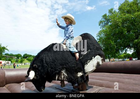 Cowboy versucht sein Glück auf dem mechanischen Bullen bleiben Stockfoto