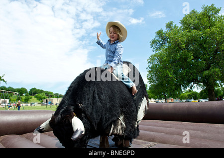 Cowboy versucht sein Glück auf dem mechanischen Bullen bleiben Stockfoto