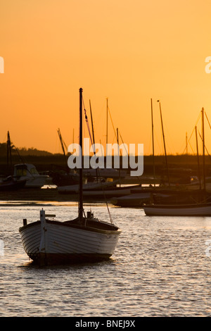 Die untergehende Sonne hinter Boote vertäut auf dem Fluss bei Burnham Overy Staithe brennen Stockfoto